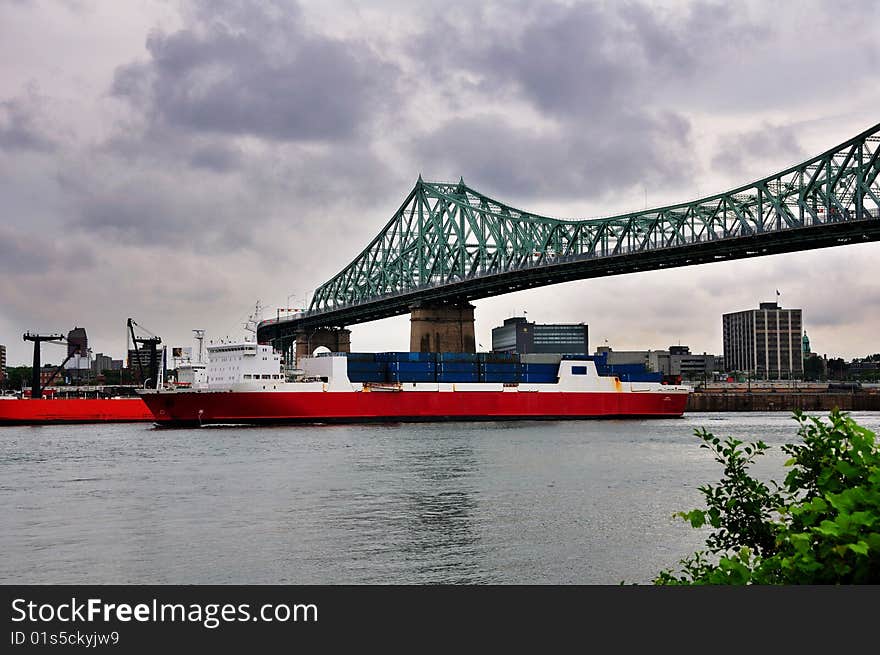 A cargo ship with containers passing through a bridge. A cargo ship with containers passing through a bridge