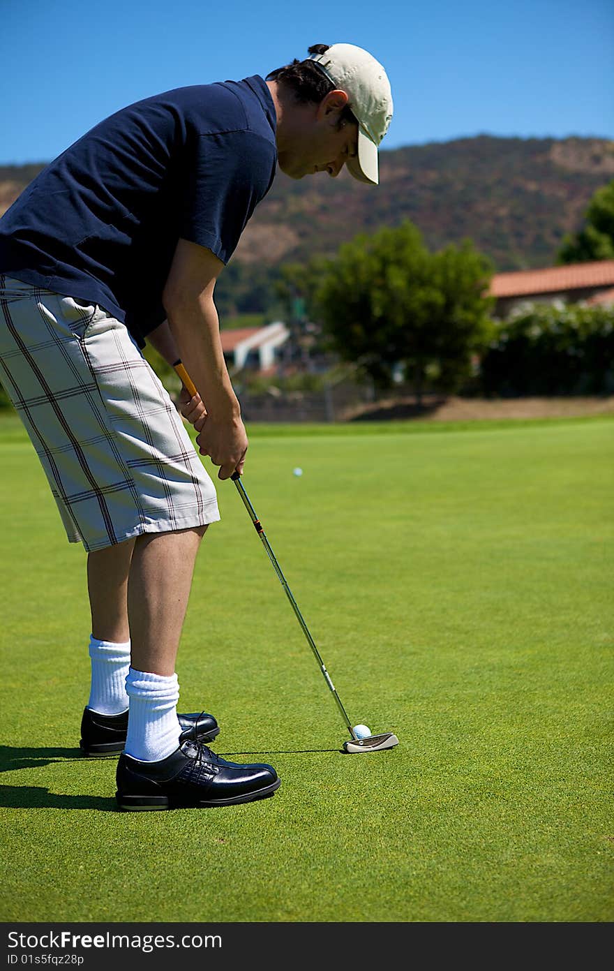 A man putting a golf ball toward the hole. A man putting a golf ball toward the hole