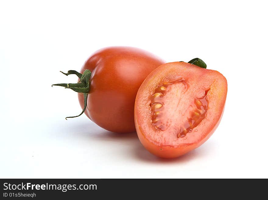 One sliced tomato in front of a whole one over a white seemless background. One sliced tomato in front of a whole one over a white seemless background.