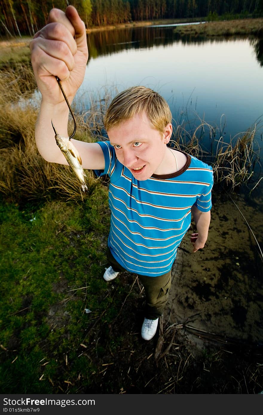 A cute guy showing off a crucian he has just caught. A cute guy showing off a crucian he has just caught