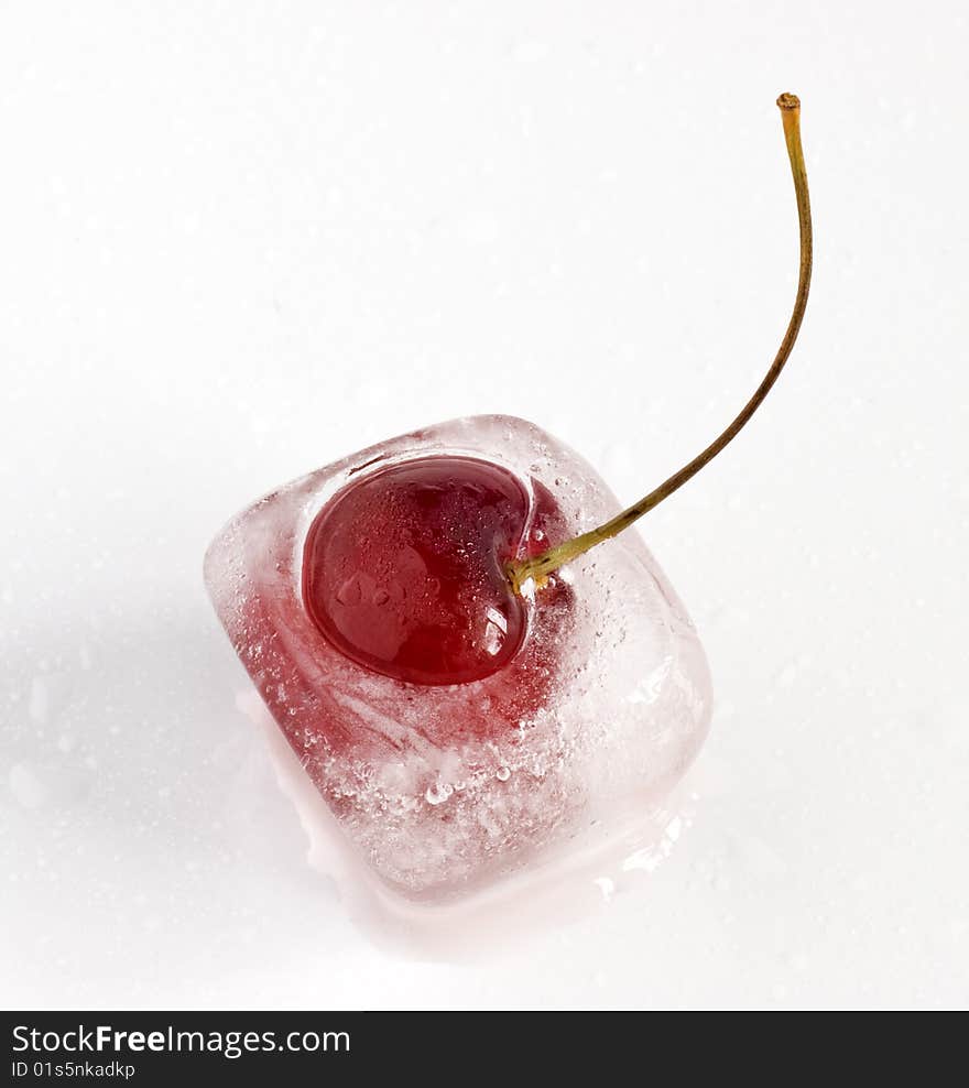 Single cherry frozen inside ice cube, melting. Single cherry frozen inside ice cube, melting.