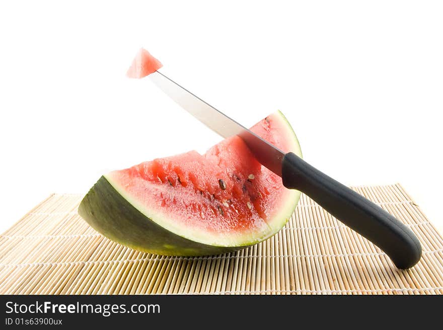 Slice of a watermelon with a knife with piece of the watermelon on white