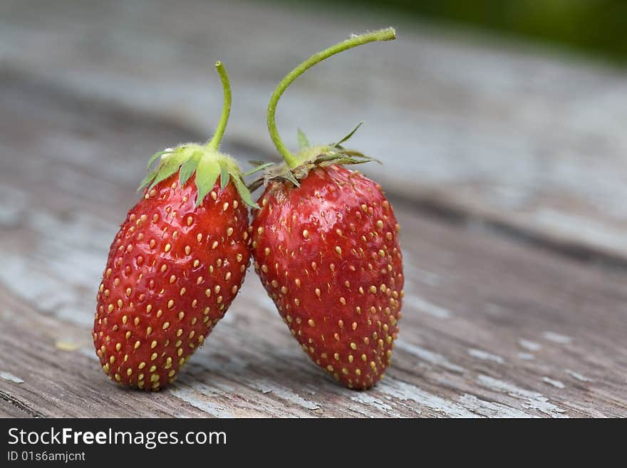 Two strawberries standing on the wooden table