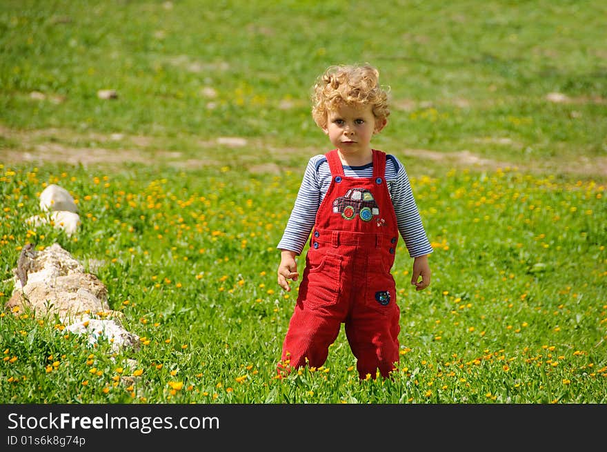 Very serious boy standing on a green grass