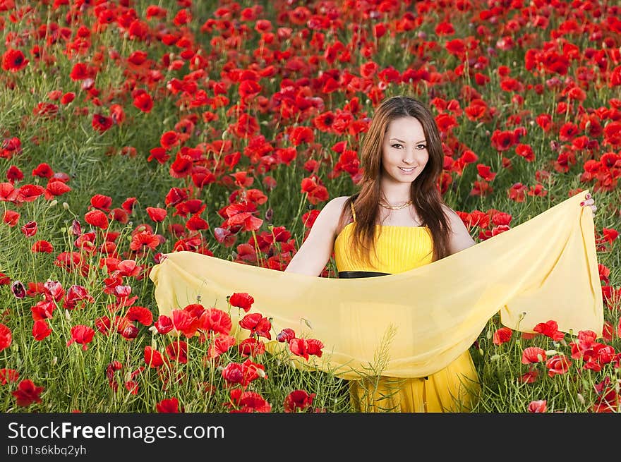 Smiling girl with yellow scarf in the poppy field