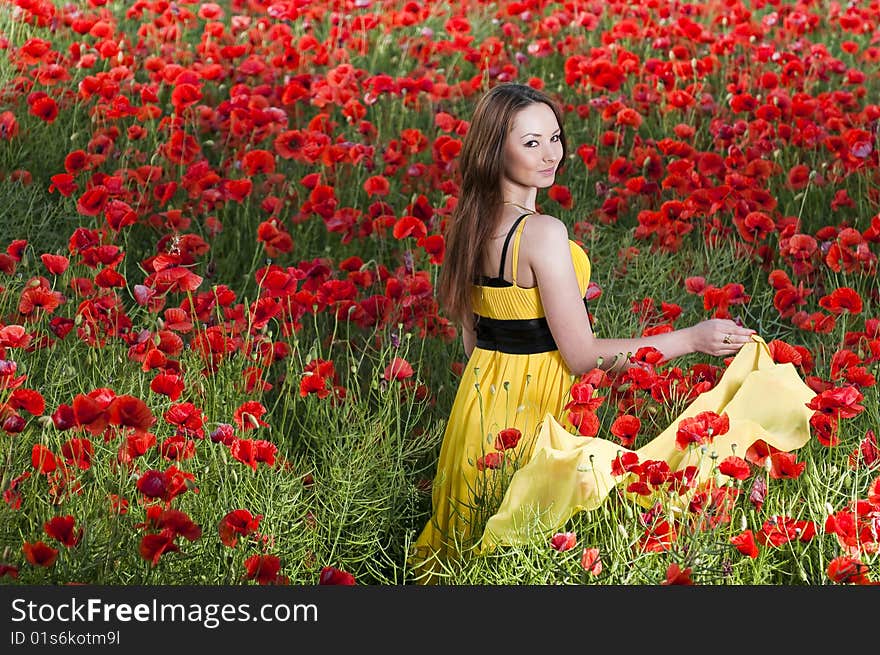 Beautiful young girl with yellow scarf in the poppy field