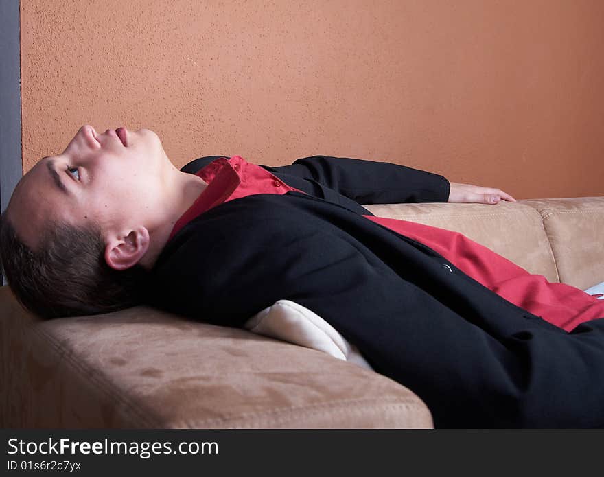 Young businessman with long hair chilling on a couch with a suit. Young businessman with long hair chilling on a couch with a suit.