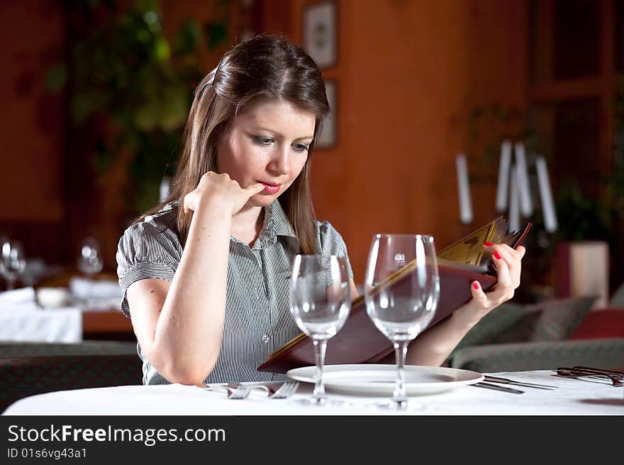 Girl chooses meal under the menu at restaurant. Girl chooses meal under the menu at restaurant