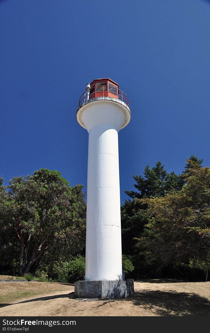 A lighthouse stands alone on a grassy hill. A lighthouse stands alone on a grassy hill