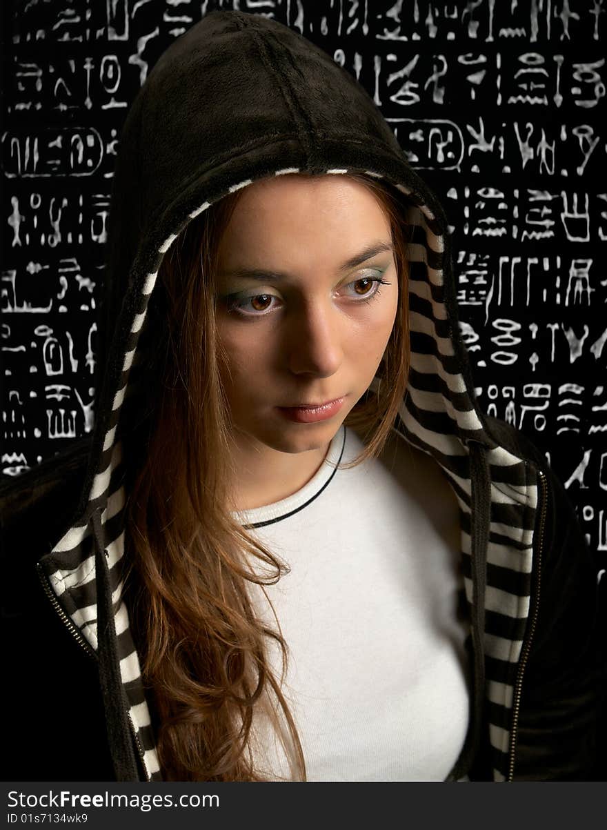 Young girl in hood against a Egypt hieroglyph background. Young girl in hood against a Egypt hieroglyph background