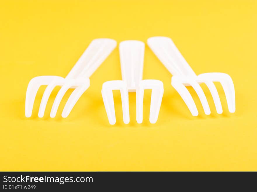 Food hunters - plastic forks isolated on yellow macro shot. Food hunters - plastic forks isolated on yellow macro shot