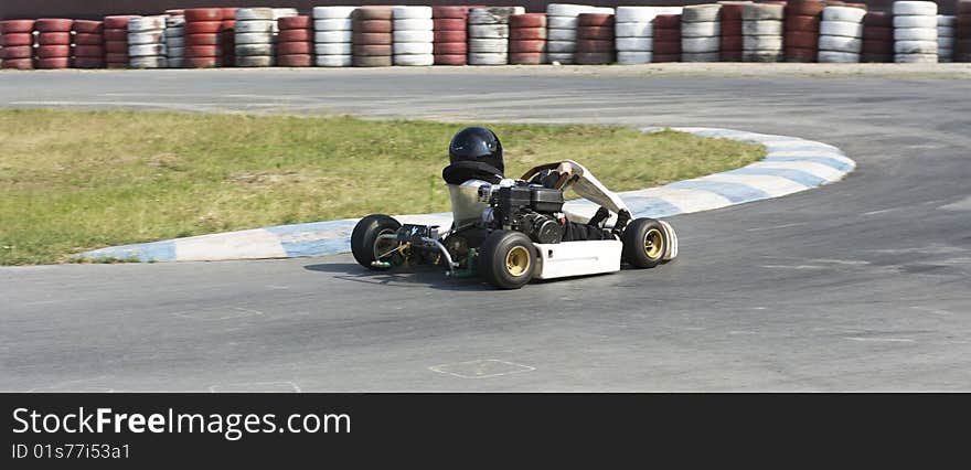 A toddler, who is actually a little bigger than the steering wheel of his kart, deftly takes the turn. A toddler, who is actually a little bigger than the steering wheel of his kart, deftly takes the turn.