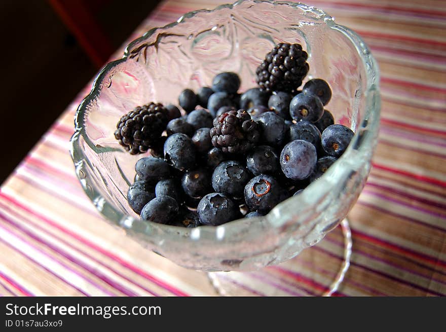 Blueberries and blackberries in a glass bowl.