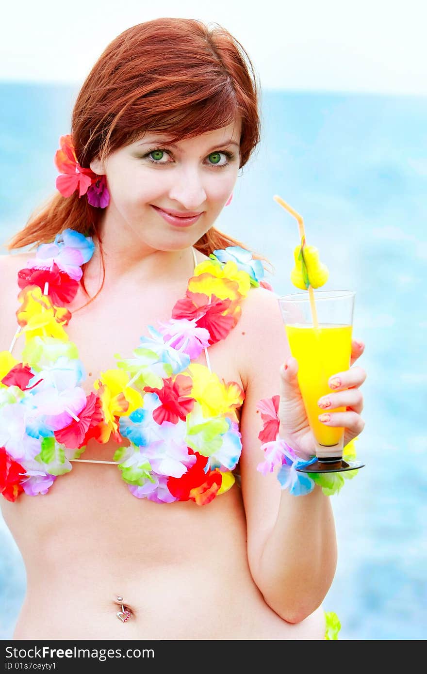 Attractve girl in bright bikini with glass of juice on sea background