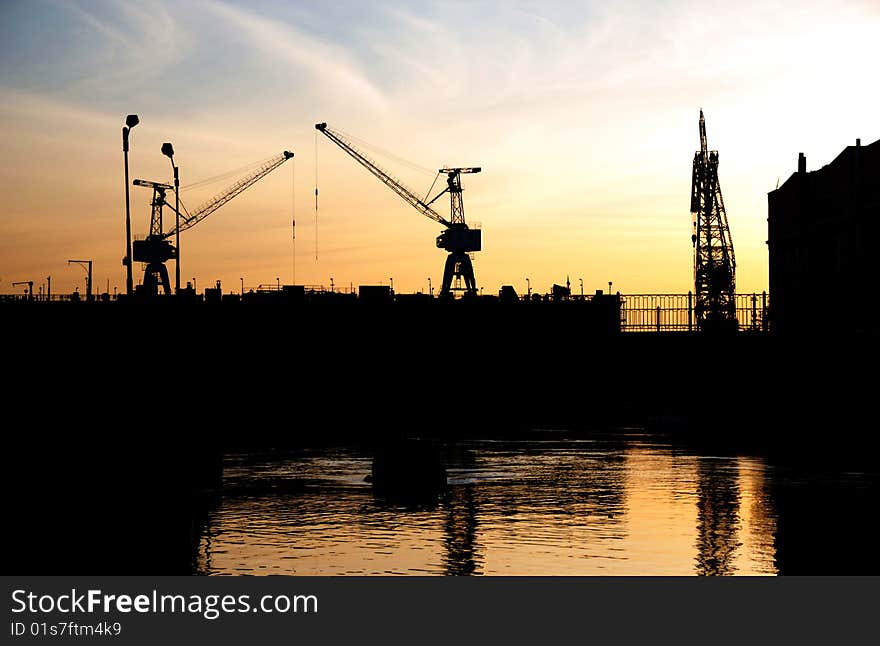 Silhouettes of Portal Cranes in a Harbor. Shot during sunset. Silhouettes of Portal Cranes in a Harbor. Shot during sunset.