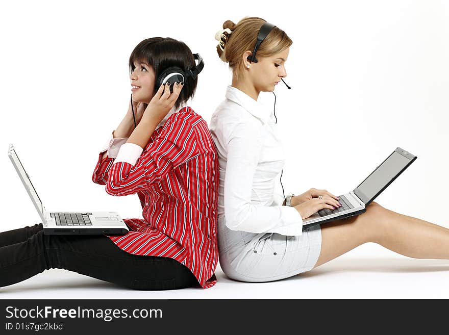 Two young women with laptops one of them listens to music, and another works. Two young women with laptops one of them listens to music, and another works