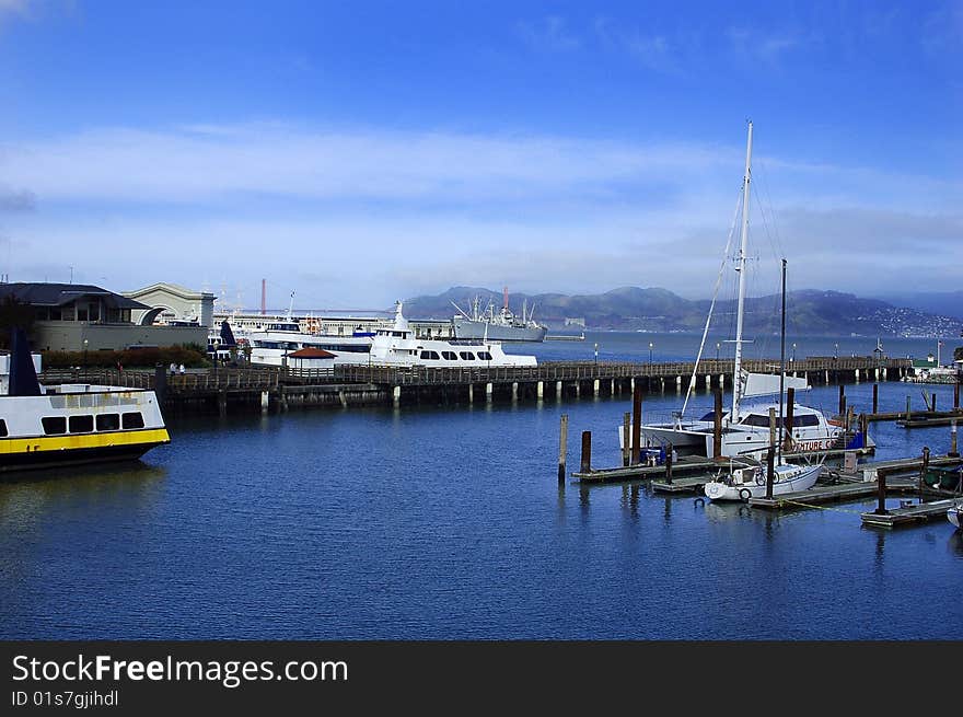 San Francisco Pier with boats and mountains in background.