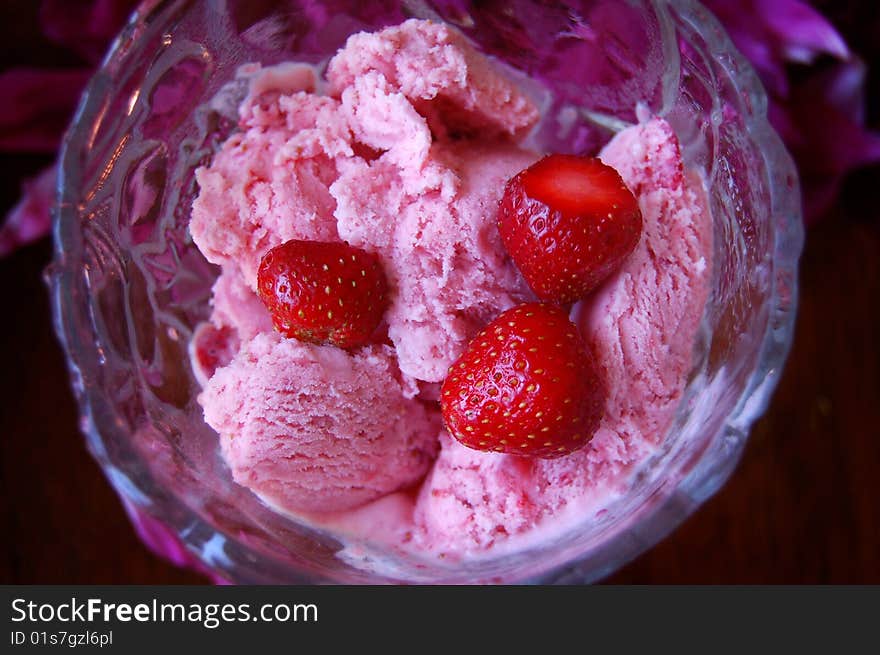 Strawberry ice cream with fresh strawberries in a glass bowl.