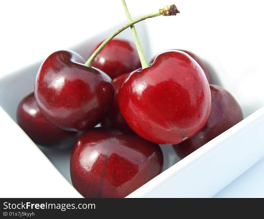 Bunch of cherries in dish against white background