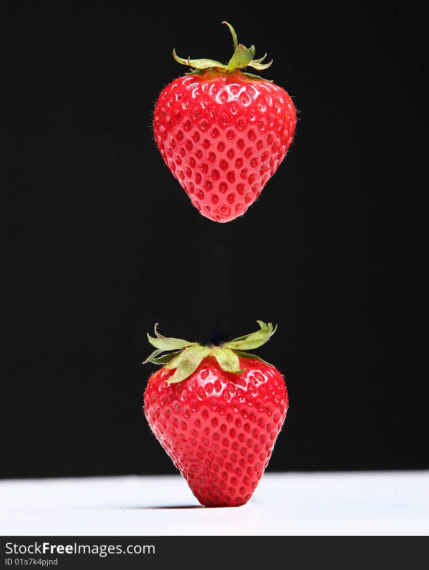 Two strawberries one suspended in air. Two strawberries one suspended in air