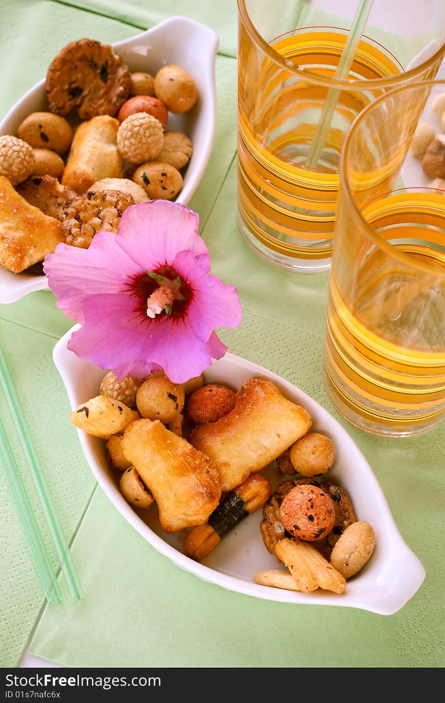 Rice snacks served with a flower and two long-drink glasses on the table. Rice snacks served with a flower and two long-drink glasses on the table