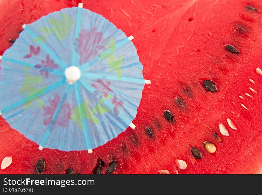 Blue umbrella will thrust in red pulp of a water-melon. Blue umbrella will thrust in red pulp of a water-melon