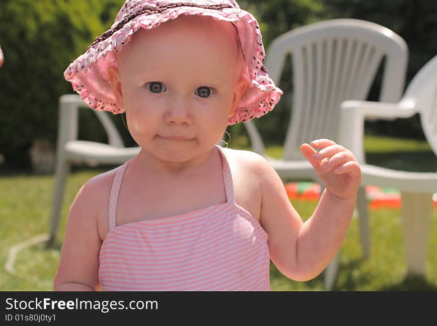 Little baby girl with a funny face in a pink hat. Little baby girl with a funny face in a pink hat