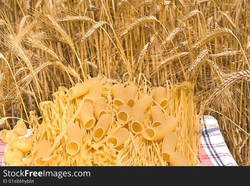 Noodles, macaroni and wheat stalks on a table in the field. Noodles, macaroni and wheat stalks on a table in the field.