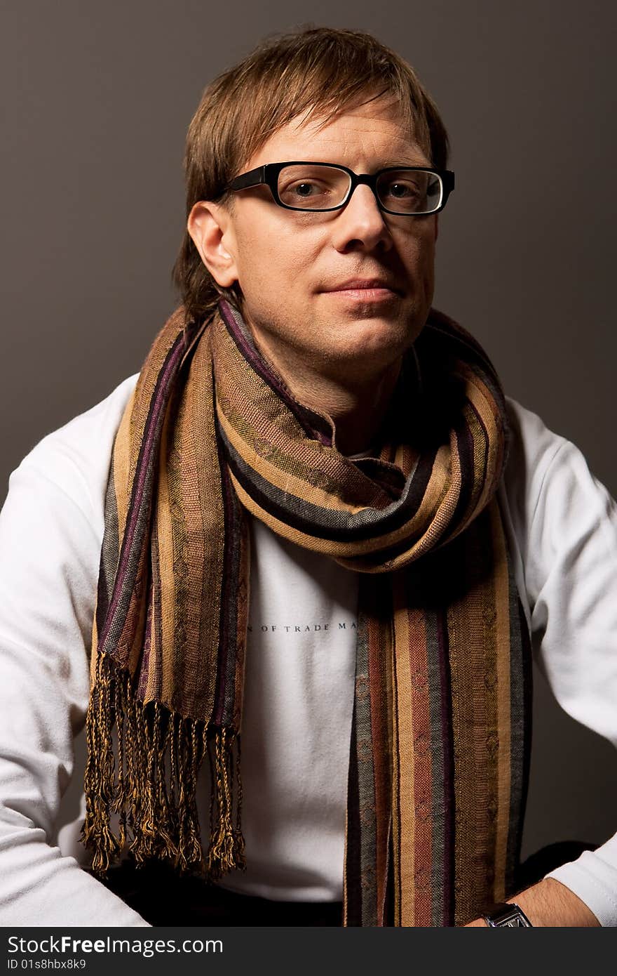 Man in glasses and scarf smiling isolated over gray