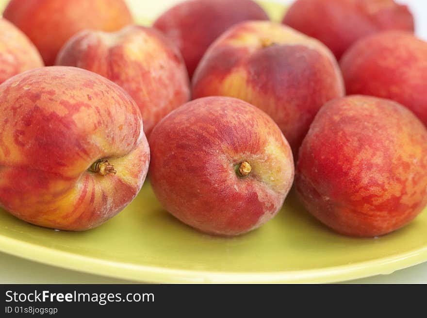 Fresh fruits: red riped peaches on green plate