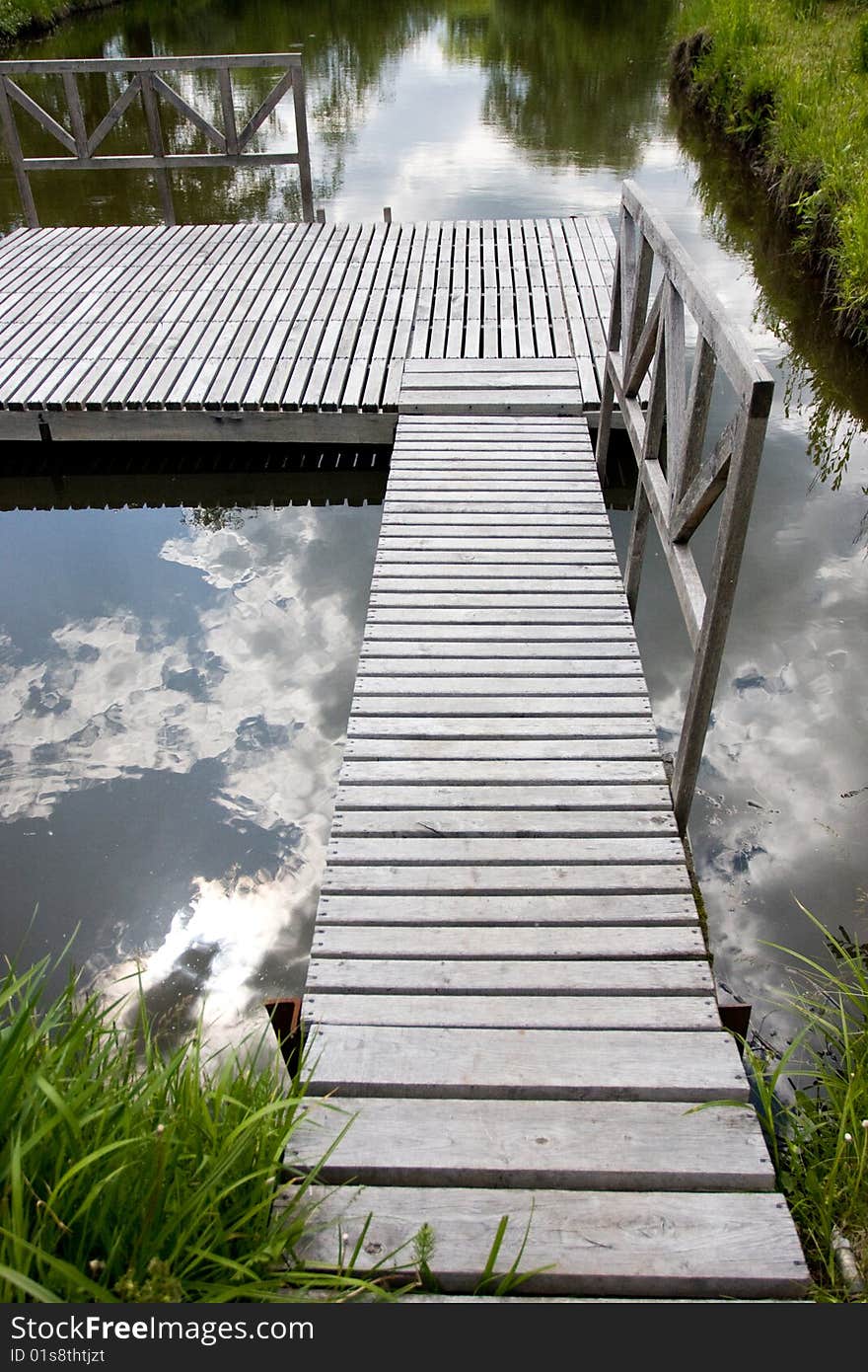 Wooden bridge and reflection of blue sky in water. Wooden bridge and reflection of blue sky in water