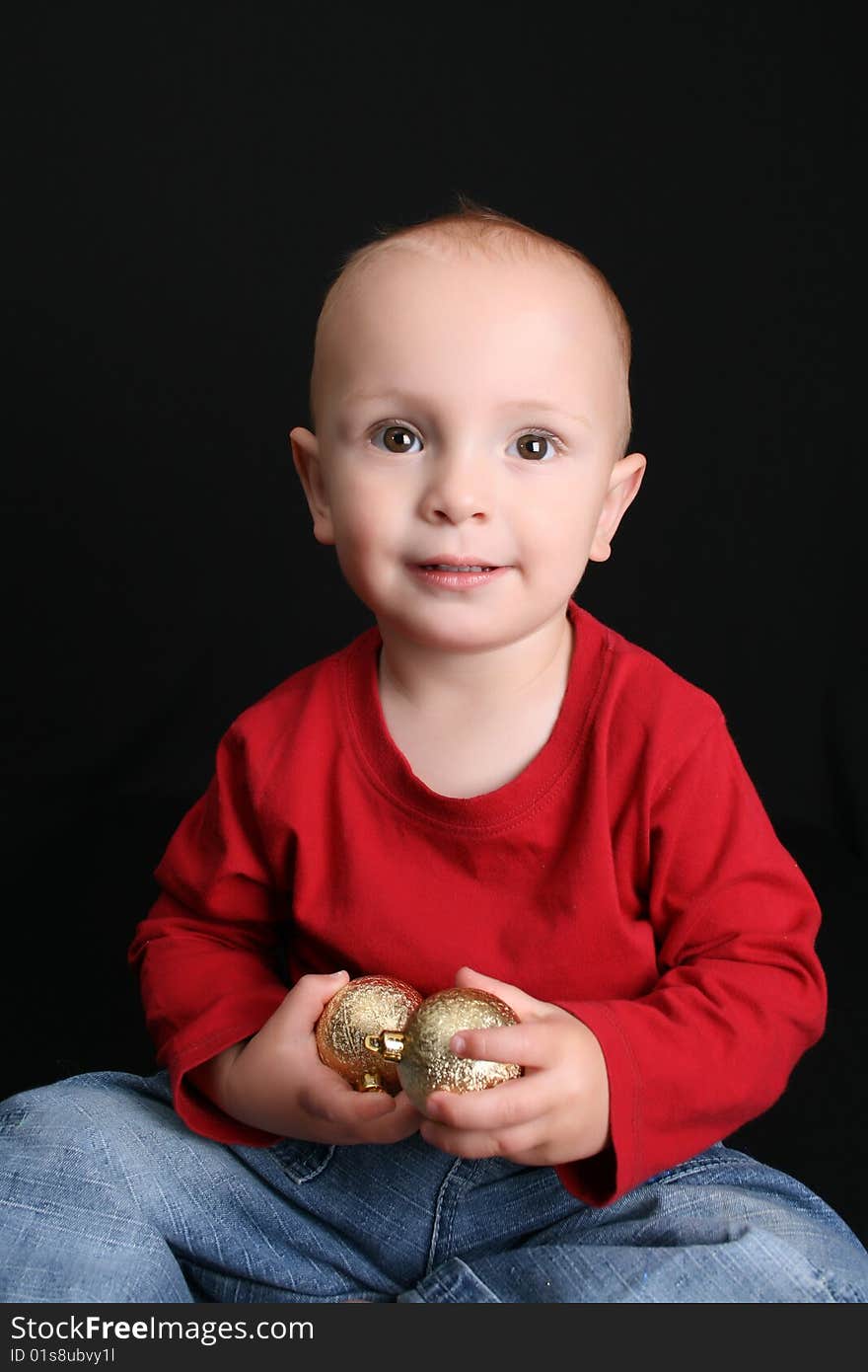 Blonde toddler against a black background with a smile