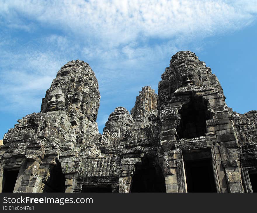 Image of a temple in angkor that has many rock formed faces.