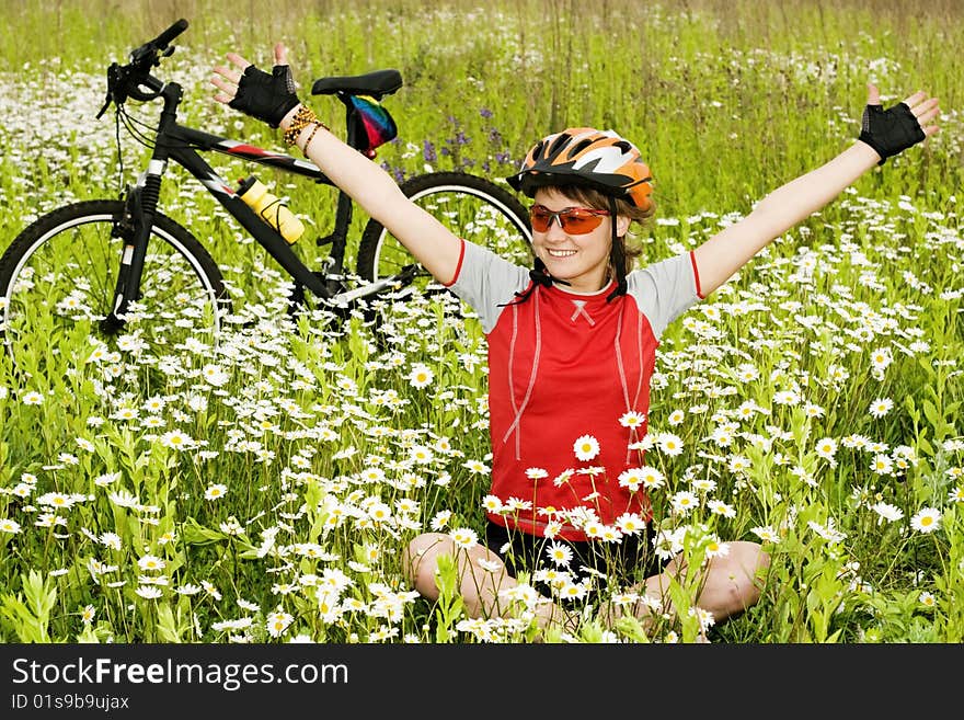 An image of a girl sitting on the grass at the bicycle. An image of a girl sitting on the grass at the bicycle