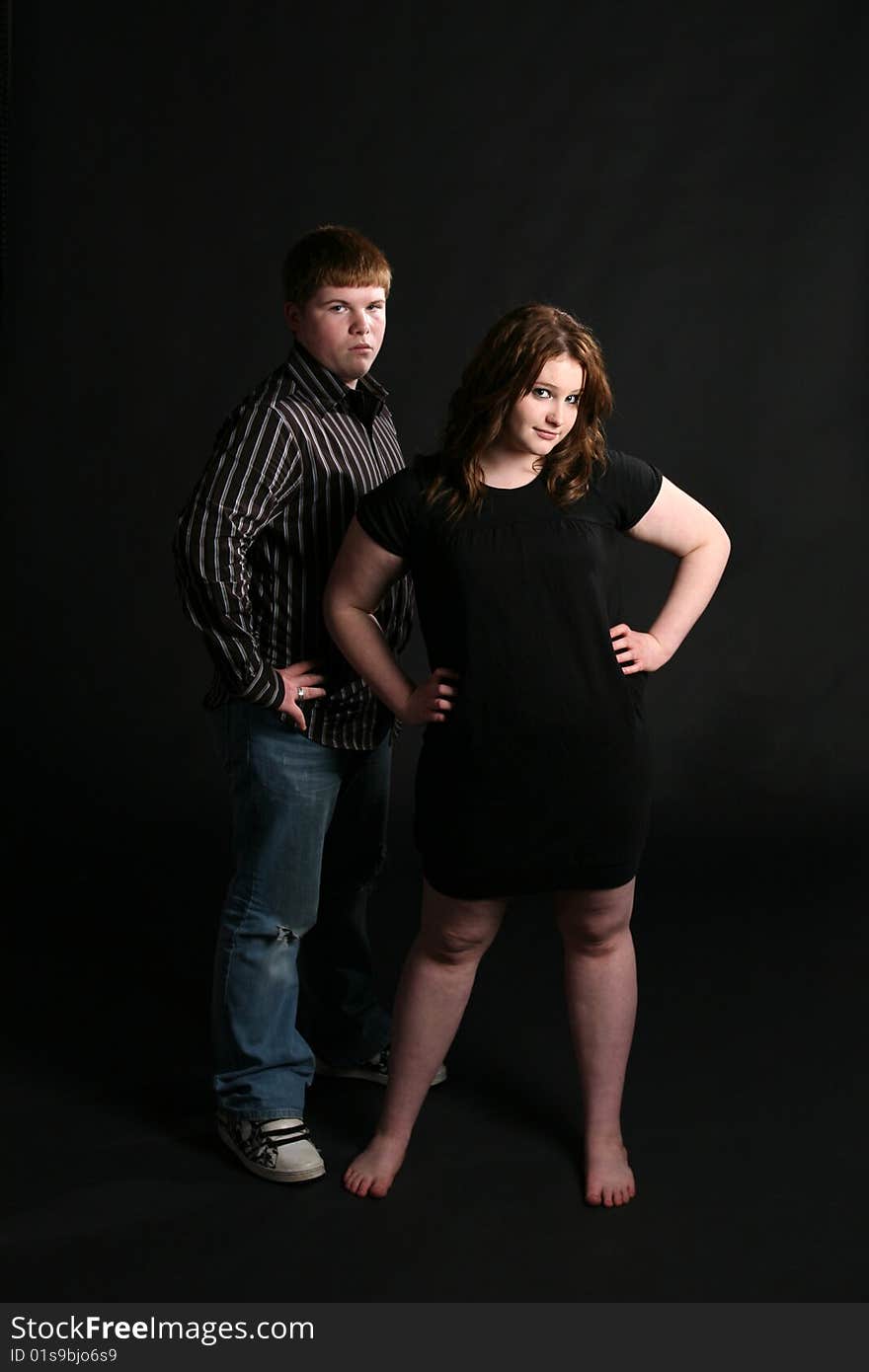 Teenage couple standing together against black background