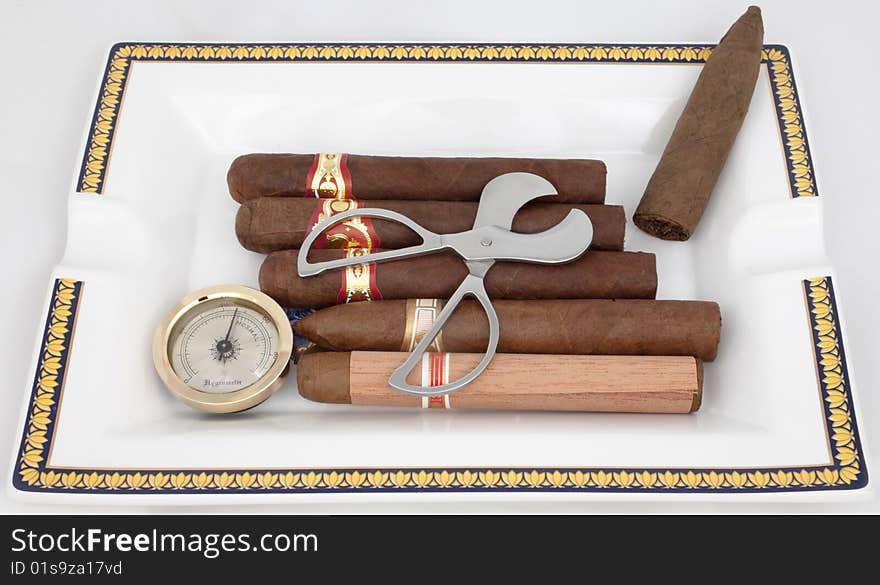 A few cigars, cutters, and hygrometer are in an ashtray