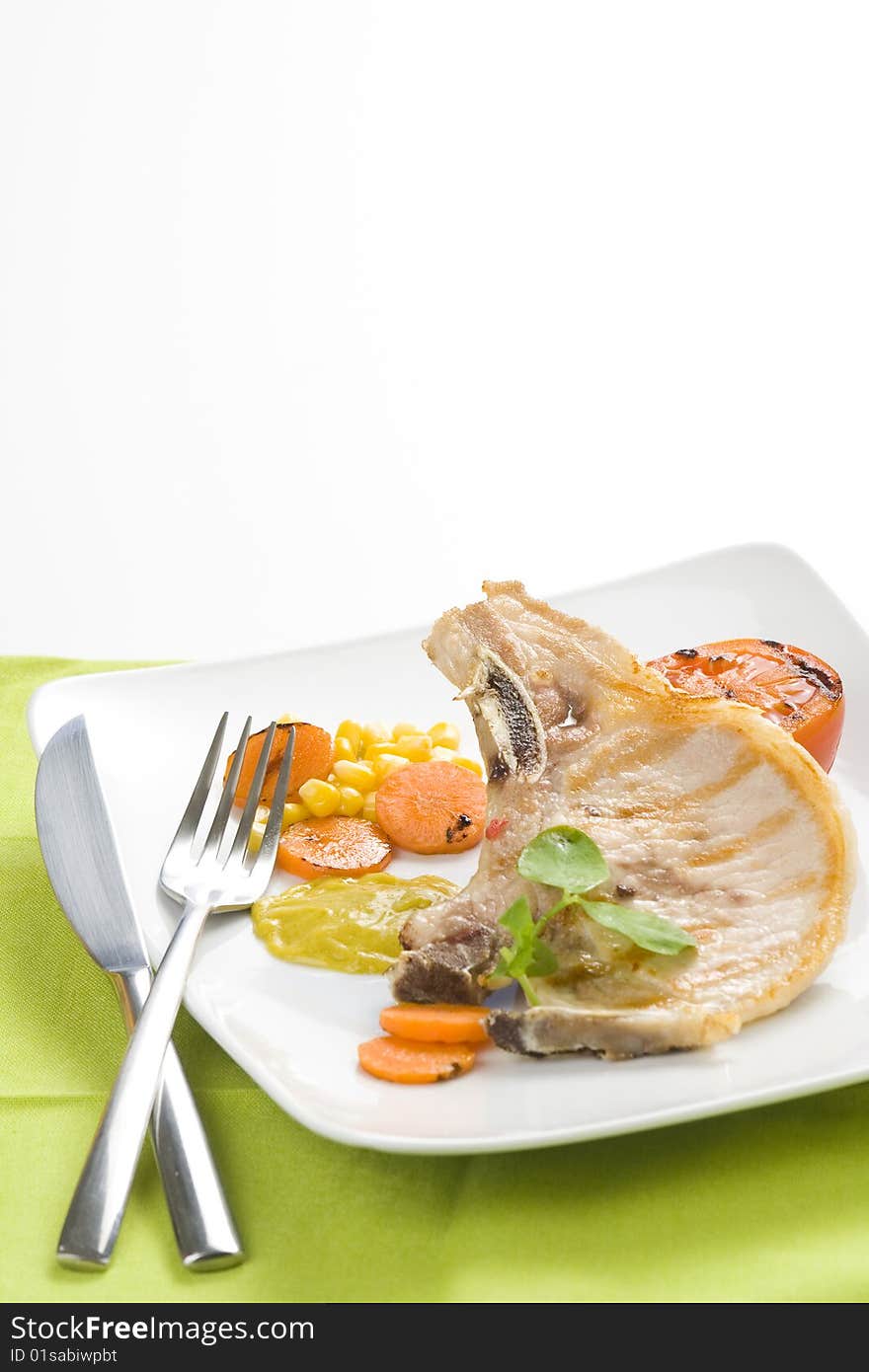 Tasty pork chop with corn carrot tomato