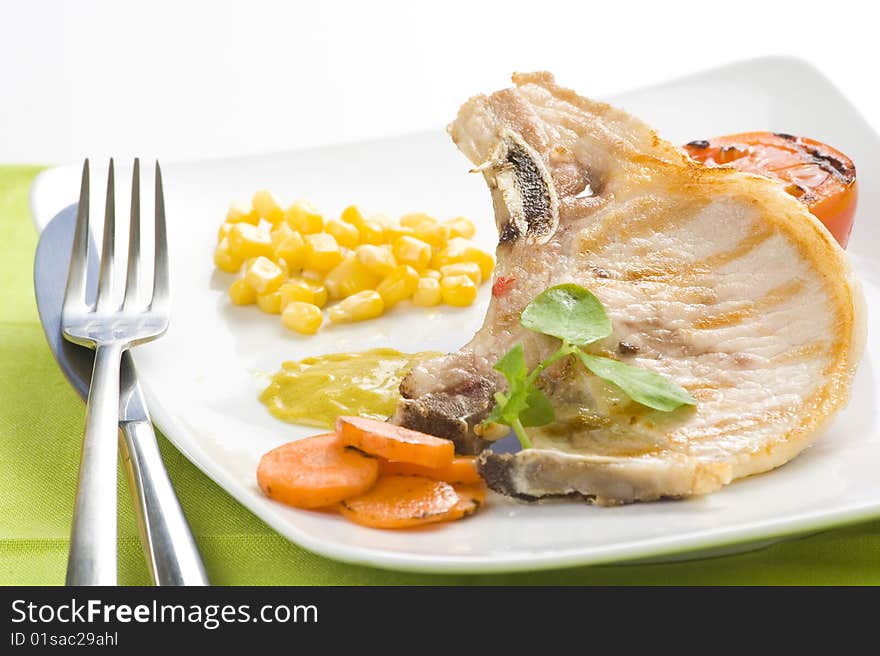 Tasty pork chop with corn carrot tomato