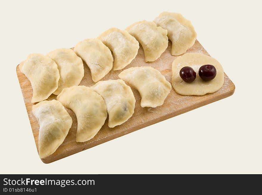 Pelmeni with a cherry on a board on a white background. Pelmeni with a cherry on a board on a white background