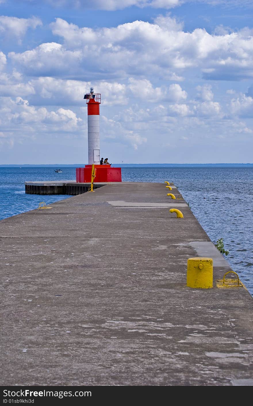 Crisp red lighthouse on the pier in Oakville, Ontario. Taken on a sunny day with mixed cloud cover.