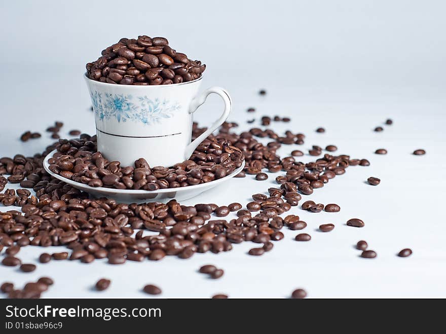 Cup of coffee beans on white background