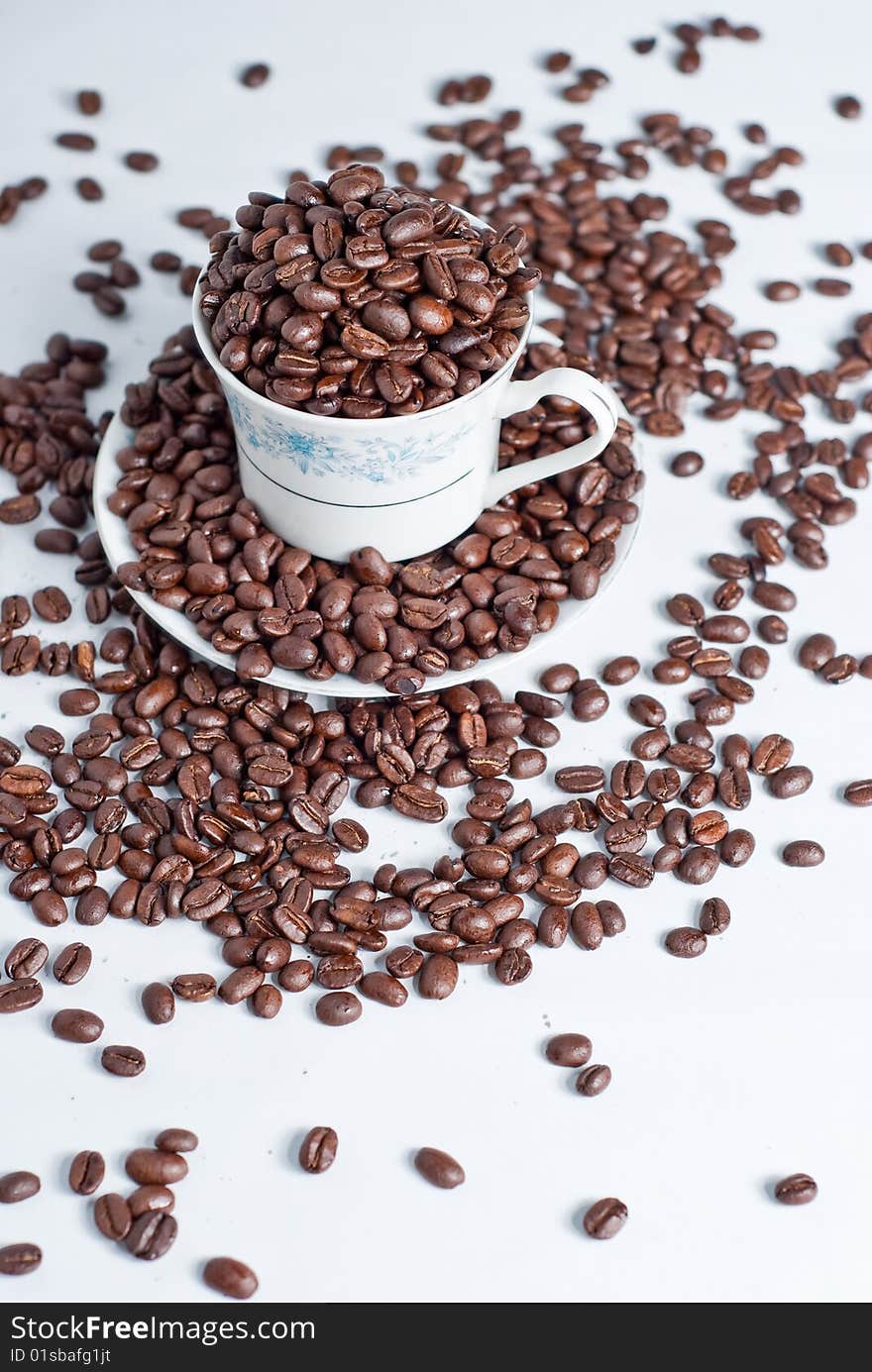 Cup of coffee beans on white background