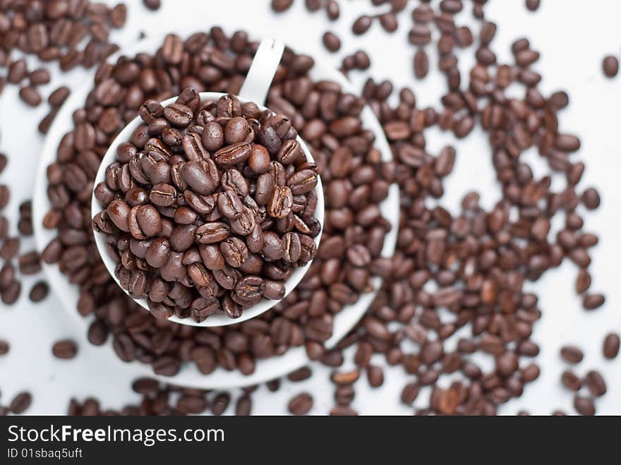 Cup of coffee beans on white background