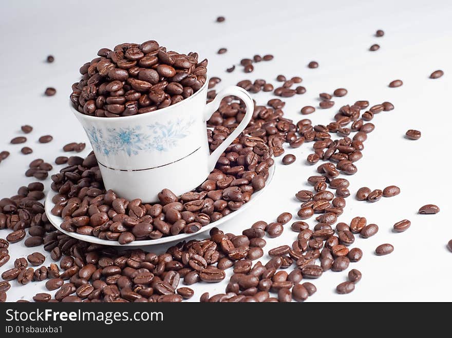 Cup of coffee beans on white background