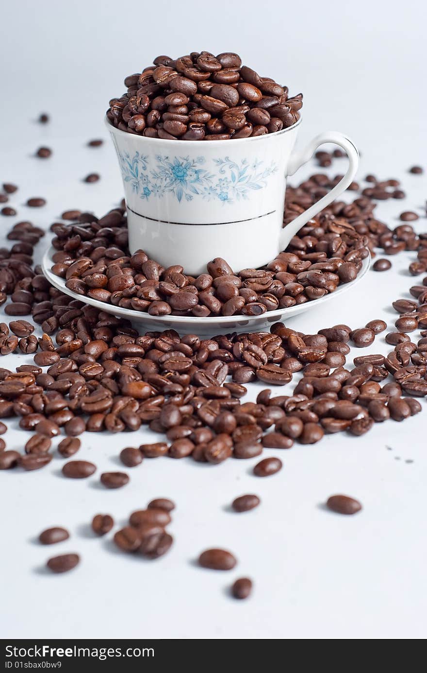 Cup of coffee beans on white background