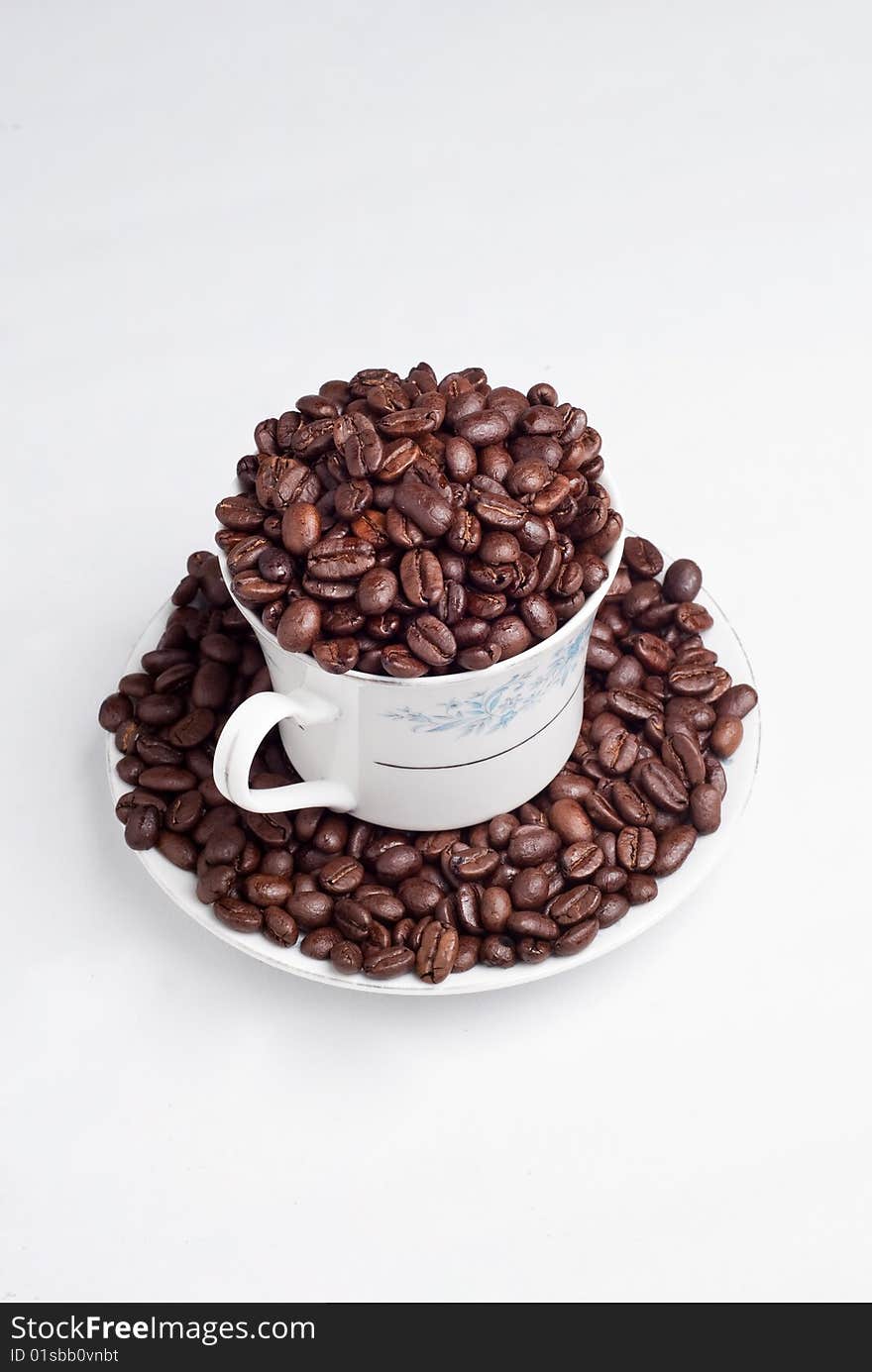 Cup of coffee beans on white background