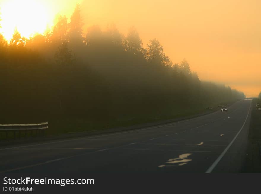 Hazy morning on highway. Lonely car moving along. Sunlights from trees. Hazy morning on highway. Lonely car moving along. Sunlights from trees