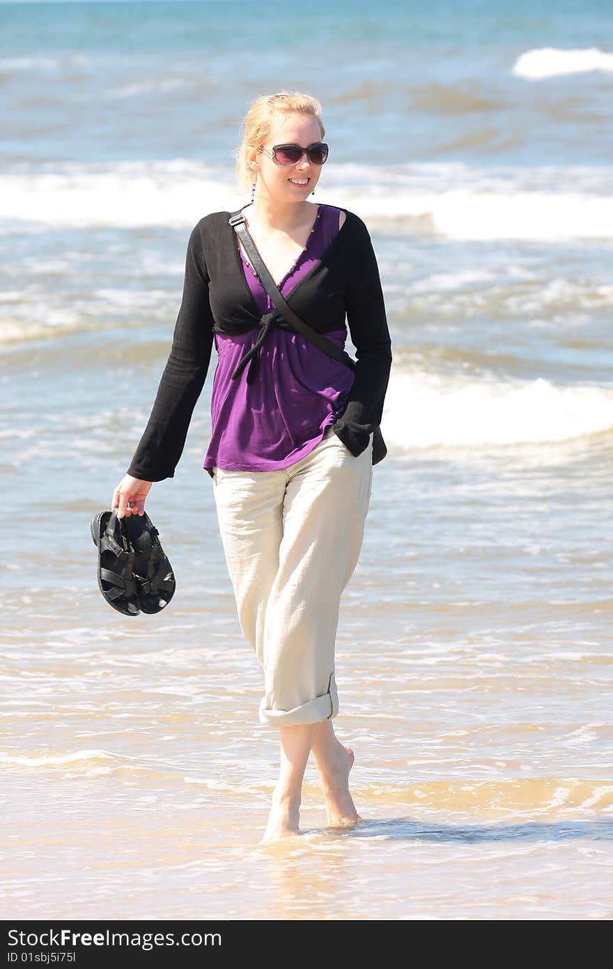 Blond smiling girl walking on the beach