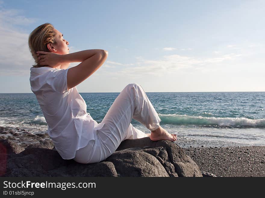 A woman is siting on the beach and relaxing. A woman is siting on the beach and relaxing.