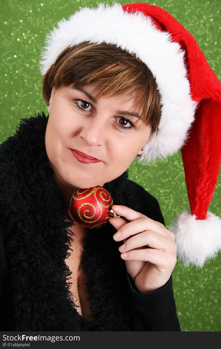 Adult female wearing a christmas hat, attempting to bite a decoration. Adult female wearing a christmas hat, attempting to bite a decoration